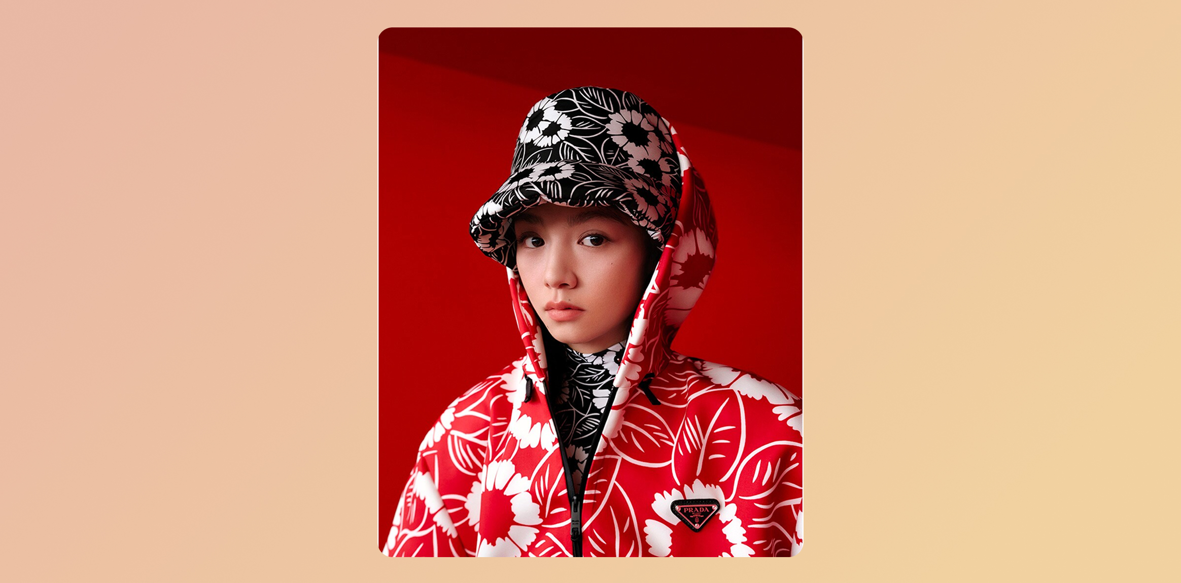 Prada's 2022 Chinese New Year campaign - Action in the Year of the Tiger. Woman in a red and white floral Prada hooded jacket with a black-and-white floral hood against a red backdrop.